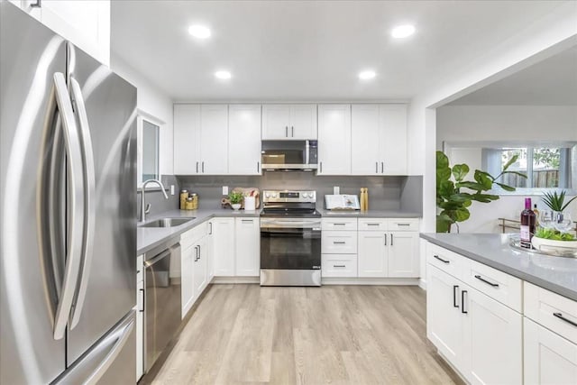 kitchen featuring sink, white cabinets, stainless steel appliances, and light wood-type flooring