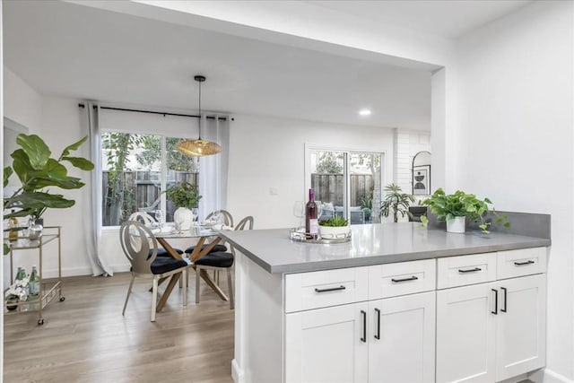 kitchen with a wealth of natural light, white cabinetry, pendant lighting, and light hardwood / wood-style flooring