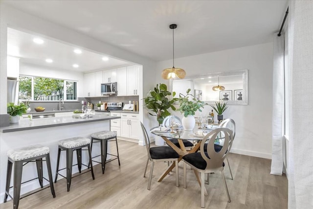 dining space with light hardwood / wood-style floors and sink