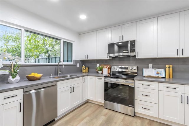 kitchen with light hardwood / wood-style flooring, sink, stainless steel appliances, and white cabinetry