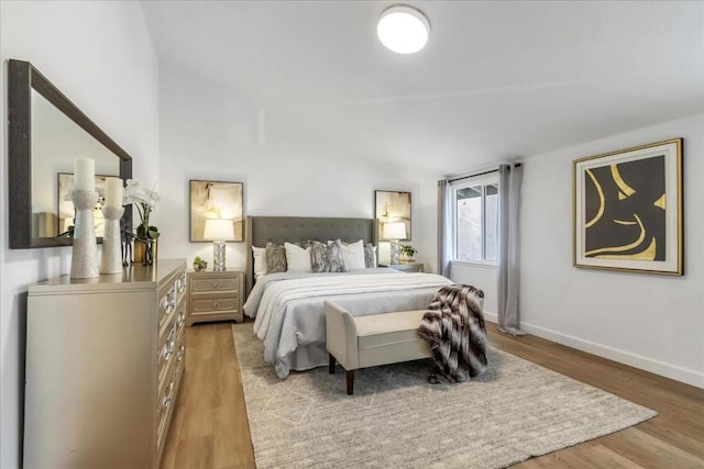 bedroom with lofted ceiling and light hardwood / wood-style floors