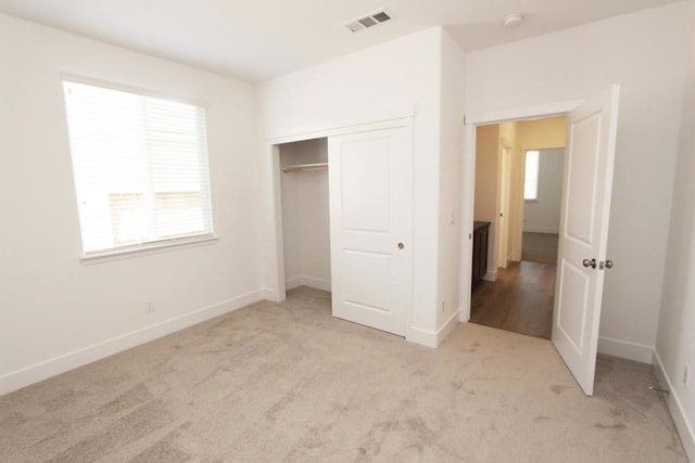 unfurnished bedroom featuring light carpet and a closet