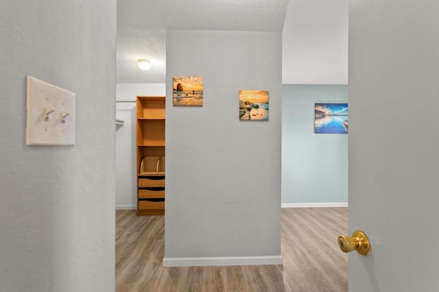 hall with a textured ceiling and light hardwood / wood-style flooring