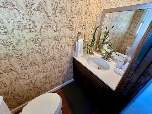 bathroom featuring wallpapered walls, toilet, baseboards, and vanity