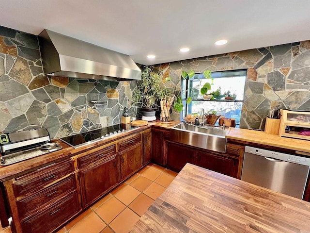 kitchen with a sink, black electric cooktop, wall chimney range hood, dishwasher, and butcher block counters
