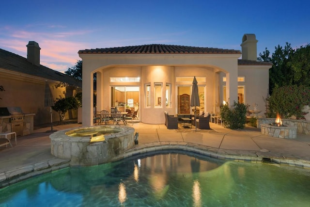 pool at dusk featuring a patio area, an in ground hot tub, area for grilling, and an outdoor living space with a fire pit