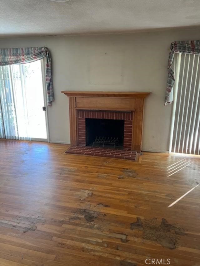 unfurnished living room featuring hardwood / wood-style flooring, a fireplace, and a textured ceiling