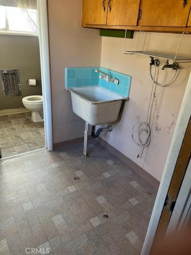 bathroom with heating unit, toilet, and sink