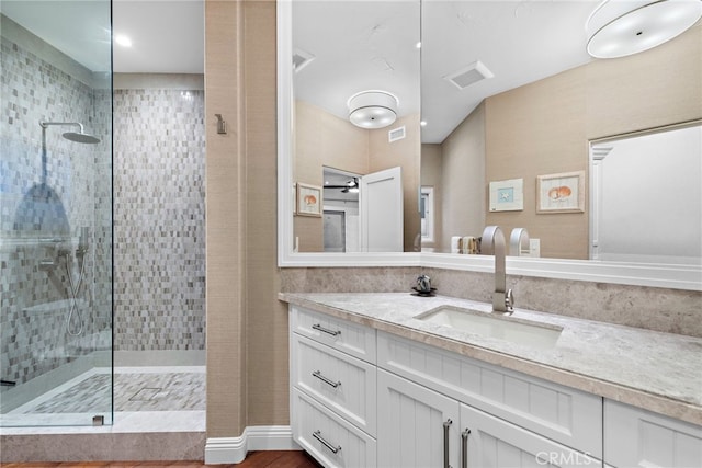 bathroom featuring tiled shower and vanity