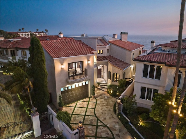 view of front of home featuring a garage, a balcony, and a water view