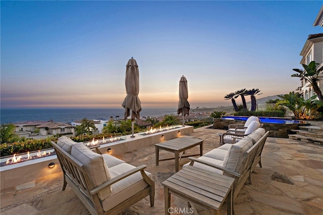 patio terrace at dusk with an outdoor living space and a water view