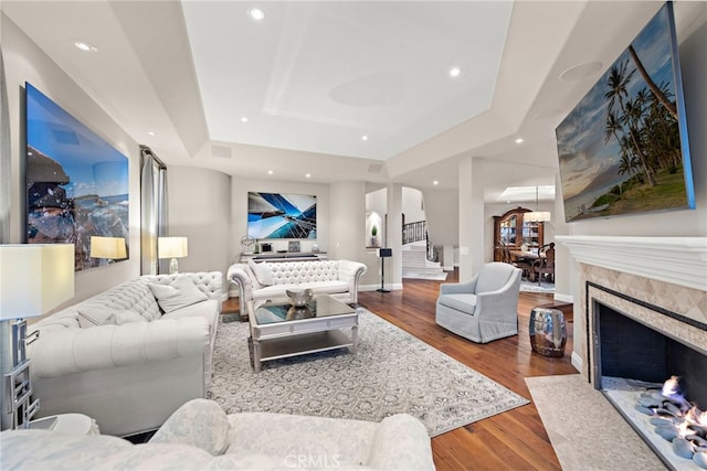 living room featuring a raised ceiling, a premium fireplace, and hardwood / wood-style floors