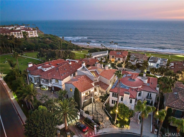 aerial view at dusk featuring a water view