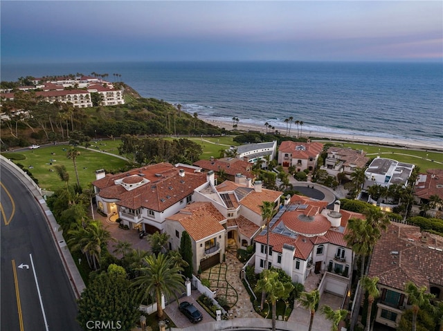 aerial view at dusk with a view of the beach and a water view