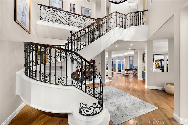 staircase with wood-type flooring and a high ceiling