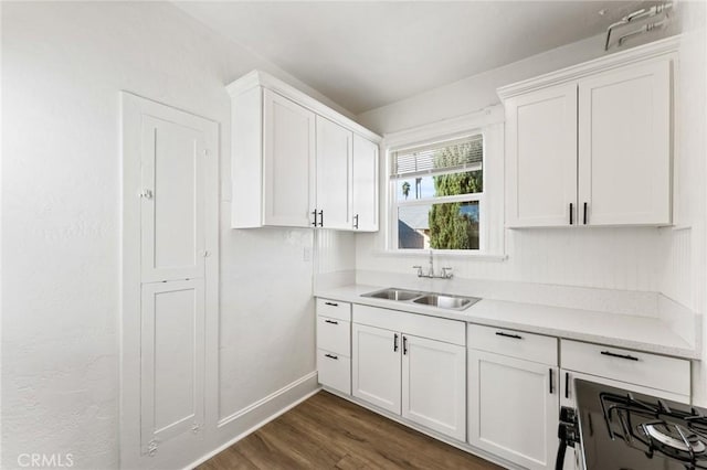 kitchen with dark hardwood / wood-style flooring, white cabinetry, sink, and stove