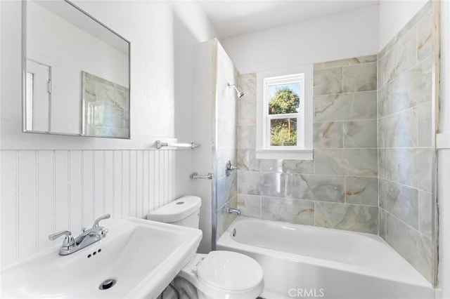 full bathroom featuring tiled shower / bath combo, toilet, and sink