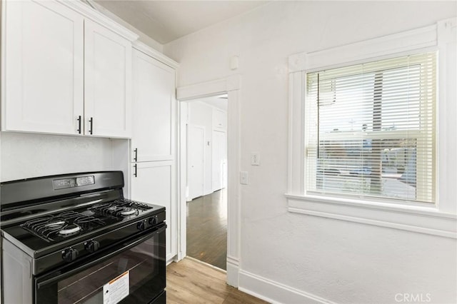 kitchen with black gas range, light wood-type flooring, and white cabinetry