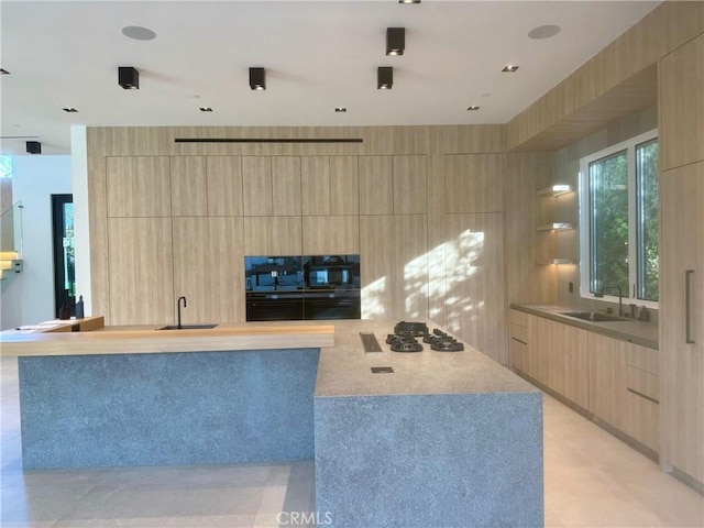 kitchen with gas stovetop, sink, light brown cabinets, and oven