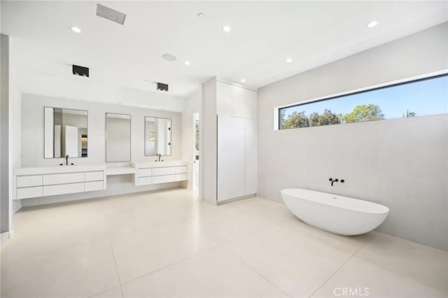 bathroom with a freestanding bath, tile patterned floors, vanity, and recessed lighting