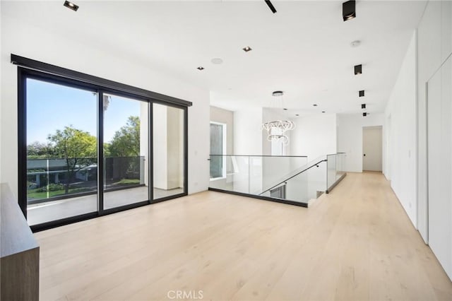 spare room with an inviting chandelier and light wood-style floors