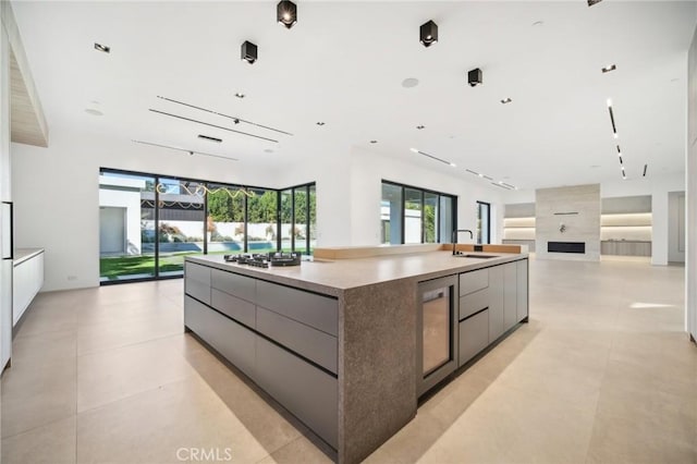 kitchen featuring a spacious island, modern cabinets, wine cooler, open floor plan, and a sink