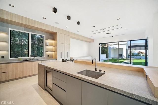 kitchen with light stone countertops, light brown cabinets, a sink, and modern cabinets