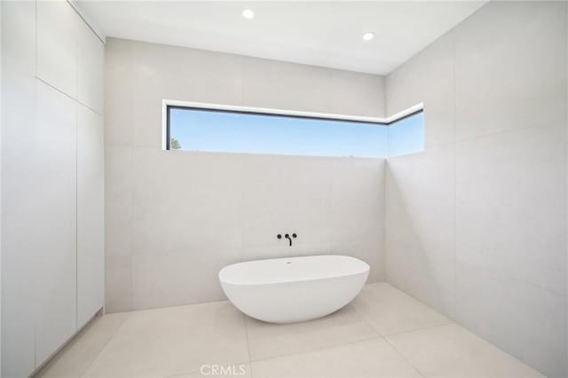 full bathroom with tile patterned flooring, tile walls, a freestanding bath, and recessed lighting