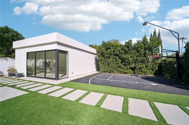 view of sport court featuring basketball hoop and a yard