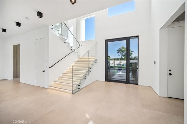 foyer entrance featuring elevator, a high ceiling, and stairway