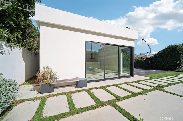 rear view of property with a patio area, fence, and stucco siding