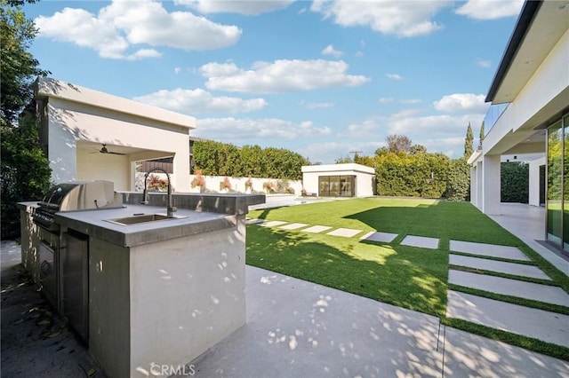 view of yard featuring a ceiling fan, a sink, an outdoor kitchen, and a patio