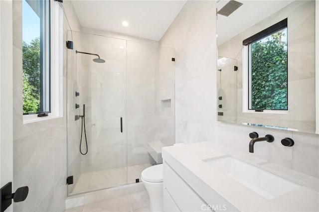 bathroom with toilet, a stall shower, tile walls, and vanity