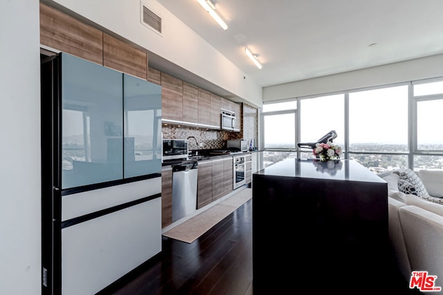 kitchen with dark hardwood / wood-style flooring, stainless steel appliances, a kitchen island, and tasteful backsplash