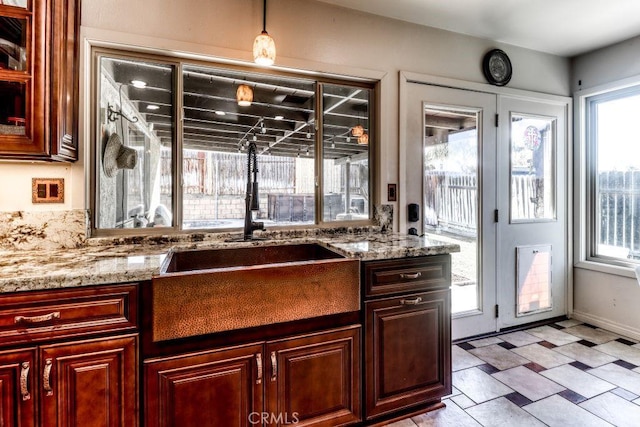 kitchen featuring sink, decorative light fixtures, plenty of natural light, and light stone countertops