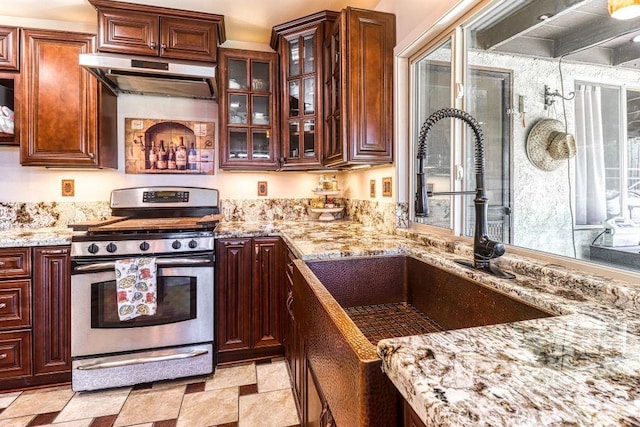 kitchen featuring stainless steel gas range and light stone counters