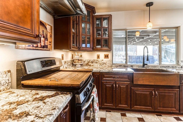 kitchen featuring sink, decorative light fixtures, stainless steel range oven, and a wealth of natural light