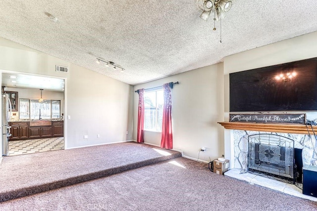 unfurnished living room featuring a stone fireplace, vaulted ceiling, a healthy amount of sunlight, and light carpet