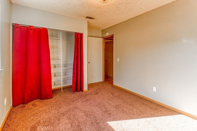 unfurnished bedroom with a textured ceiling, carpet floors, and a closet