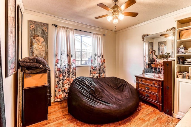 living area featuring ornamental molding, a textured ceiling, ceiling fan, and light hardwood / wood-style floors