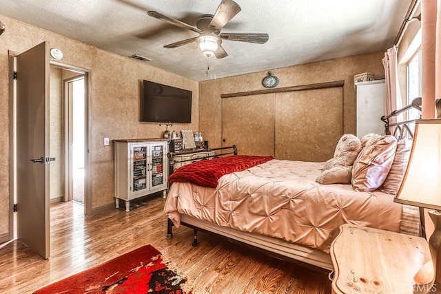 bedroom featuring ceiling fan, a textured ceiling, and wood-type flooring