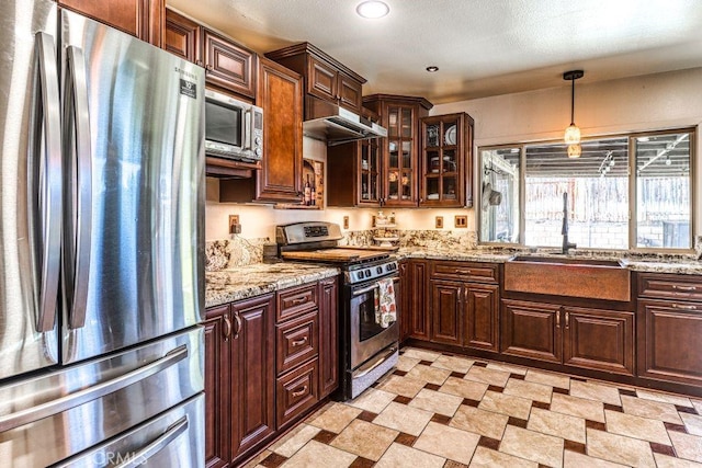 kitchen with decorative light fixtures, light stone countertops, appliances with stainless steel finishes, and sink