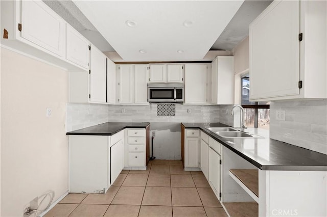 kitchen featuring decorative backsplash, light tile patterned floors, white cabinetry, and sink