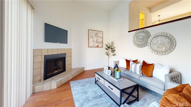 living room with a tile fireplace and light hardwood / wood-style flooring