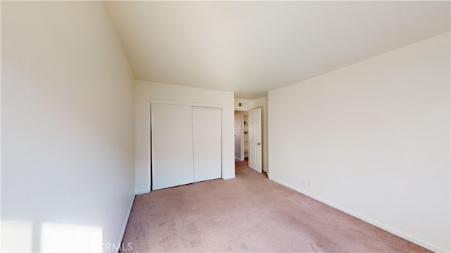 unfurnished bedroom featuring light carpet and a closet