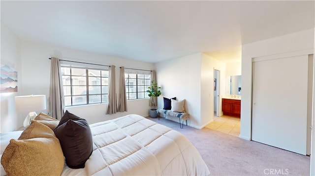 bedroom featuring connected bathroom and light colored carpet