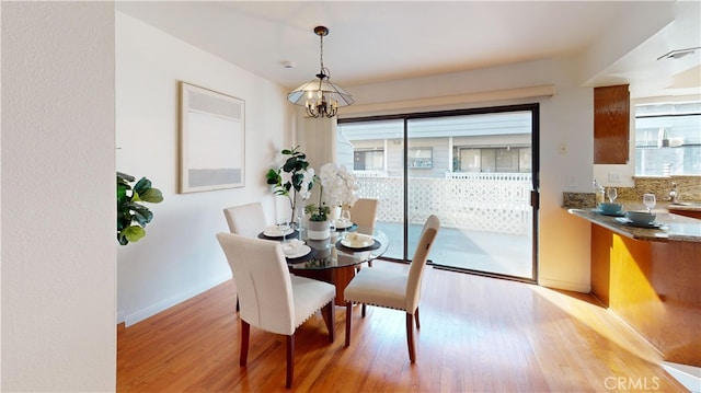 dining room with wood-type flooring, a wealth of natural light, and a chandelier