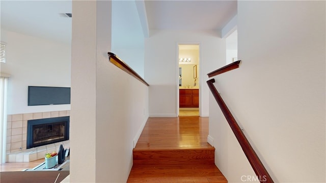 stairway featuring a tile fireplace and wood-type flooring