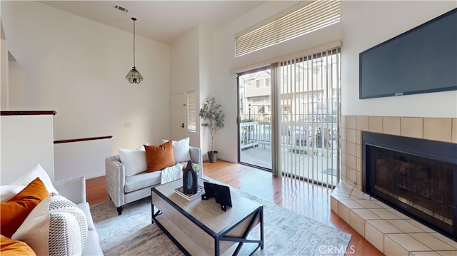 living room with wood-type flooring and a tiled fireplace