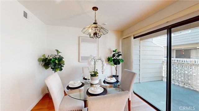 dining area featuring hardwood / wood-style flooring and a notable chandelier